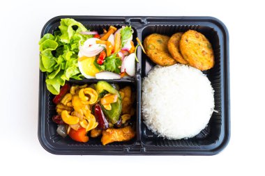 Modern Asya pirinç kutusu yemeye hazır, kaju fıstıklı kızarmış tavuk, balık köftesi ve plastik kutuda baharatlı yumurta salatası..