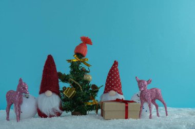 Noel ağacının etrafında hediyeler olan Noel cüceleri. Pembe geyik. Mutlu Noeller..