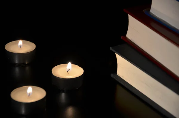 Três velas acesas e velho livro no escuro — Fotografia de Stock