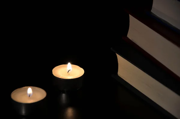 两个燃烧的蜡烛和老书在黑暗中 — 图库照片
