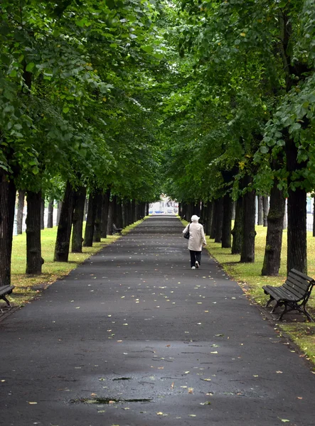 Old woman is walking through the alley in the city — Stock Photo, Image