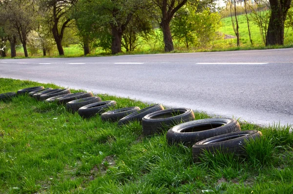 Neumáticos viejos se colocan junto a la carretera vacía . — Foto de Stock