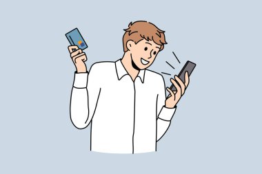 Mutlu genç adam kredi kartıyla cep telefonundan alışveriş yapıyor.