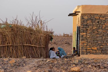 Shingetti. Moritanya 'da. Ekim 06, 2021. Bir sazdan bir binanın gölgesinde yaşayan bir köy ailesi sıcak bir Afrika gününde gün batımında açık havada çay içer..