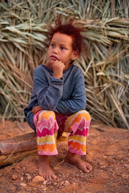 Te-n-Tamdej. Moritanya 'da. Ekim 06, 2021. Küçük bir kız, Sahra Çölü 'nün eteklerindeki kırsal bir barakanın yanında, kafası elinde duran bir tahta parçasının üzerinde oturuyor..