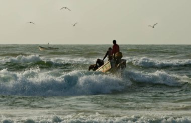 Saint-Louis. Senegal. October 11, 2021. Every day at dawn fishermen on long wooden boats go out to sea fishing with difficulty overcoming coastal waves.