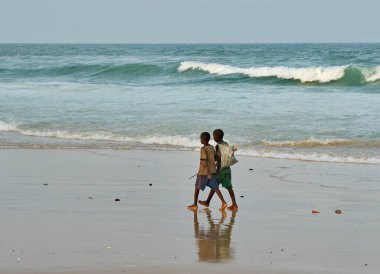 Saint-Louis 'de. Senegal. 10 Ekim 2021. Balıkçı köyünden iki çocuk Atlantik Okyanusu 'nun kumlu sahillerinde yalınayak yürüyor..