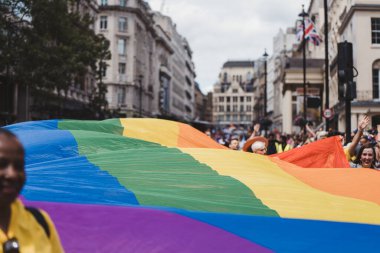 London / UK - 02/07/2022: People with huge rainbow flag celebrating London LGBTQ Pride Parade