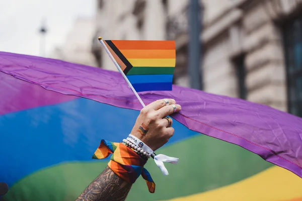 Londra / İngiltere - 02 / 07 / 2022: Londra LGBTQ Onur Yürüyüşünü kutlayan dev gökkuşağı bayrağına sahip insanlar
