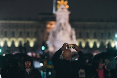 Londra (124; İngiltere - 2022.09.08) Kraliçe Elizabeth 'in ölümünden sonra Buckingham Sarayı' nın dışındaki yağmurun altında insanlar yas tutuyor ve çiçekler getiriyorlar.