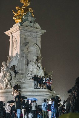 Londra (124; İngiltere - 2022.09.08) Kraliçe Elizabeth 'in ölümünden sonra Buckingham Sarayı' nın dışındaki yağmurun altında insanlar yas tutuyor ve çiçekler getiriyorlar.