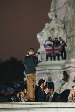 Londra (124; İngiltere - 2022.09.08) Kraliçe Elizabeth 'in ölümünden sonra Buckingham Sarayı' nın dışındaki yağmurun altında insanlar yas tutuyor ve çiçekler getiriyorlar.