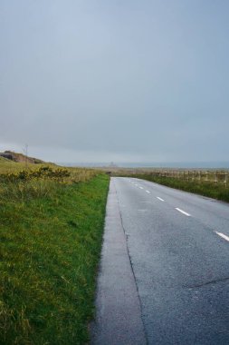 Bulutlu bir günde Jersey Adası 'ndaki Le Braye Sahili' ne giden güzel bir yol.