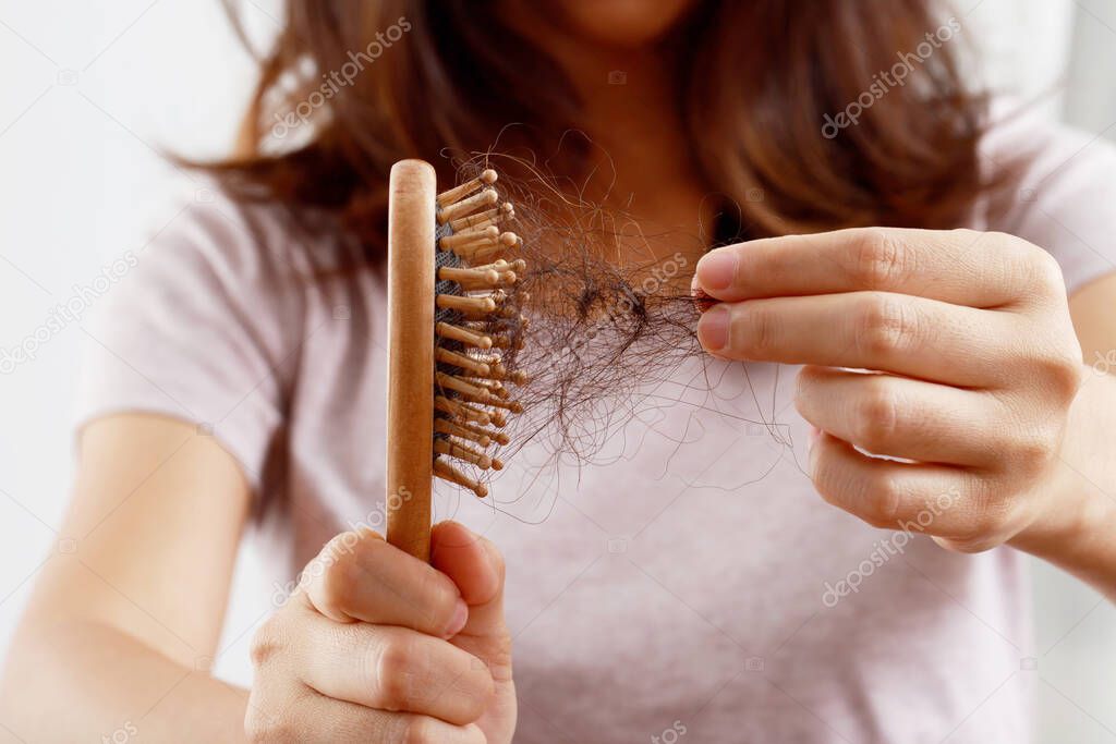 Rear view young woman worried about Hair loss problem, hormonal disbalance, stress concept. Many hair fall after combing in hair brush in hand. Female untangled her hair with a comb, Health care