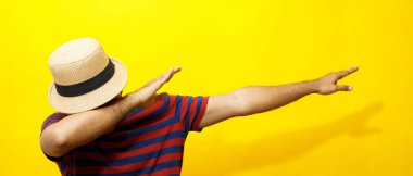 Hipster 'lı genç adam portresi. Sıradan bir genç adam. Kırmızı çizgili tişört ve şapka takıyor. Hareketli duygular kolları genişletiyor stüdyo portrelerinde utangaç, sarı arka plan..