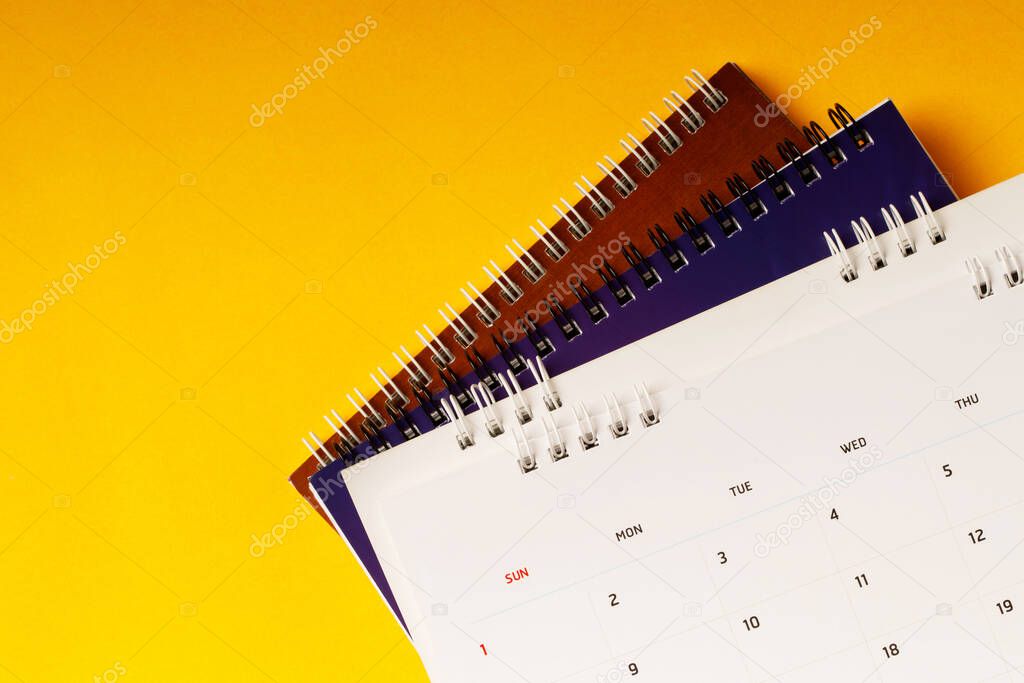 close up top view calendar schedule to make appointment meeting or manage timetable each day lay on yellow background for planning work and travel concept.