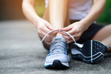 Koşu ayakkabıları. Yolda koşmak için bağcıklarını bağlayan bayan sporcu. Koşucu kravatları antrenmana hazırlanıyor. Spor yaşam tarzı. Boşluk afişini kopyala.