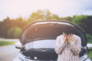 Kızgın adam, kırık bir arabanın önünde dur ve yardım çağır.