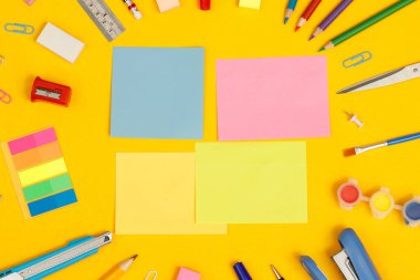 Üst görünüm not defterleri ve aksesuarlar okuldaki kütüphanede öğrenim görüyor sarı arkaplan fikir eğitimi 