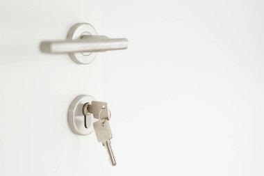 Ev şeklindeki anahtarlıkta bir kapının kilidinde gümüş anahtarlık var. Emlakçı konutları ve daireleri satın alma kavramı.