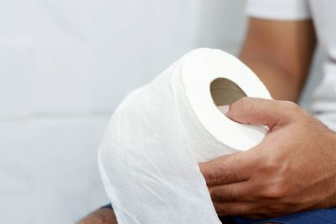 Adam ishalden muzdarip. Tuvalet kapağının önünde kağıt mendil tutuyor. Banyoda kabızlık. Mide ağrısı ve hijyen tedavisi, sağlık hizmetleri 