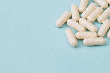 Yukarıdan bir sürü ilaç ve beyaz hap geliyor, mavi arka planda düşüyor. ağrı kesiciler ve uyuşturucu kullanımı kavramı.