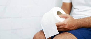 Adam ishalden muzdarip. Tuvalet kapağının önünde kağıt mendil tutuyor. Banyoda kabızlık. Mide ağrısı ve hijyen tedavisi, sağlık hizmetleri 