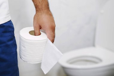 Adam ishalden muzdarip. Tuvalet kapağının önünde kağıt mendil tutuyor. Banyoda kabızlık. Mide ağrısı ve hijyen tedavisi, sağlık hizmetleri 