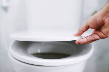 Adamın eli tuvalet kapağını açıyor.