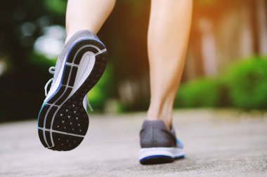 Sporcu kadın ayak koşucu yolu açık havada koşuyor. Spor yapan bir adamın ayakkabısına yakın. Sonbaharda doğa ve taşların arasında koşuyor..