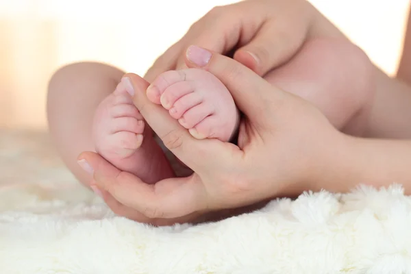 Los pies de un niño siendo sostenidos en las manos de su madre — Foto de Stock
