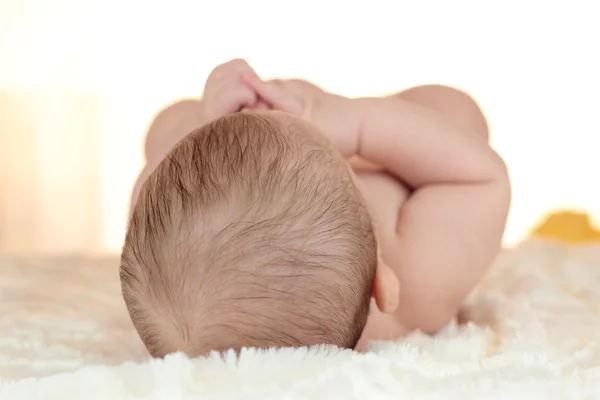 Retrato de un bebé recién nacido acostado en la cama con la parte posterior de la cabeza mostrando con un hermoso rizo en el cabello —  Fotos de Stock