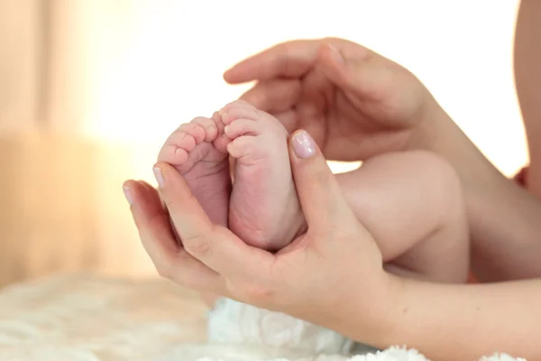 Los pies de un niño siendo sostenidos en las manos de su madre — Foto de Stock