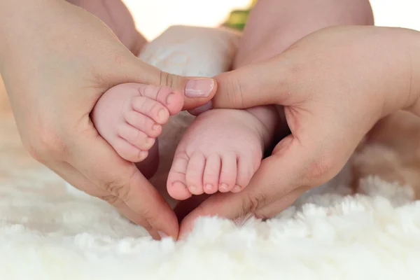 Los pies de un niño siendo sostenidos en las manos de su madre — Foto de Stock