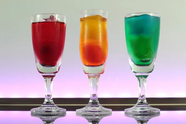 Closeup of a line of colourful cocktails resting on the bar with led lighting at a club — Stock Photo, Image