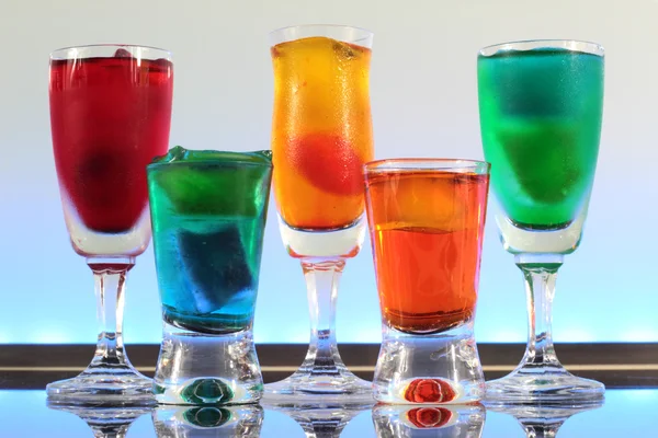Primer plano de una línea de cócteles coloridos que descansan en el bar con iluminación led en un club —  Fotos de Stock