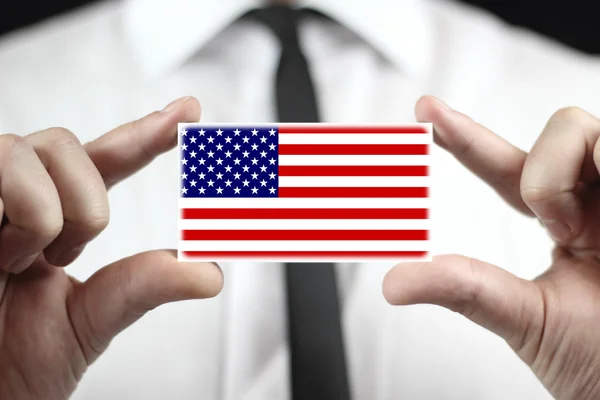 Бизнесмен, держащий визитную карточку с флагом США — стоковое фото
