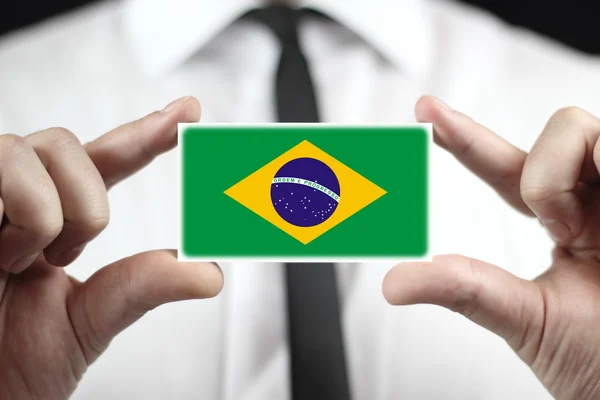 Empresário segurando um cartão de visita com uma bandeira do Brasil — Fotografia de Stock