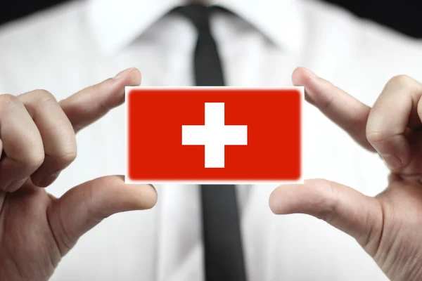 スイス連邦共和国の旗とのビジネス カードを保持している実業家 — ストック写真