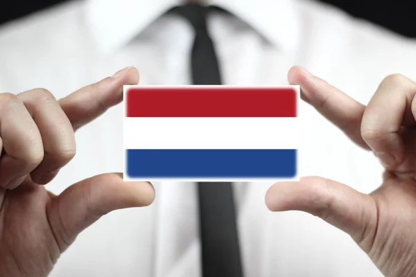 Kartvizit Hollanda bayrağı tutarak işadamı — Stok fotoğraf
