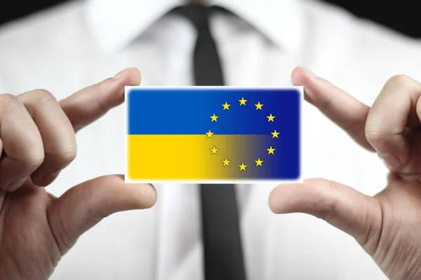 Geschäftsmann mit Visitenkarte mit EU- und ukrainischer Flagge — Stockfoto