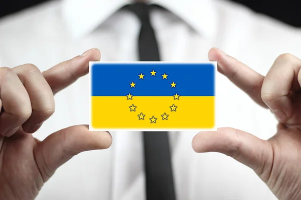Podnikatel drží vizitku s vlajkou eu a Ukrajina — Stock fotografie