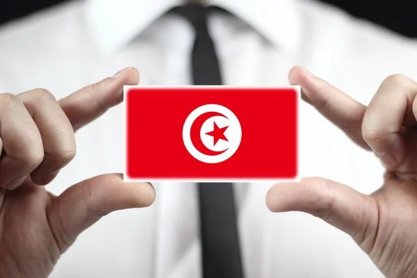 Affärsman som innehar ett visitkort med Tunisien flagga — Stockfoto