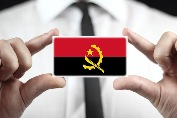 Бизнесмен, держащий визитную карточку с флагом Анголы — стоковое фото