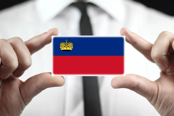Affärsman som innehar ett visitkort med lichtenstein flagga — Stockfoto