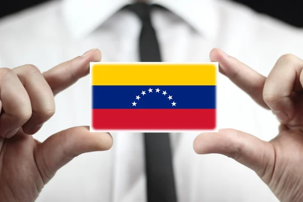 Zakenman houden een visitekaartje met venezuela vlag — Stockfoto