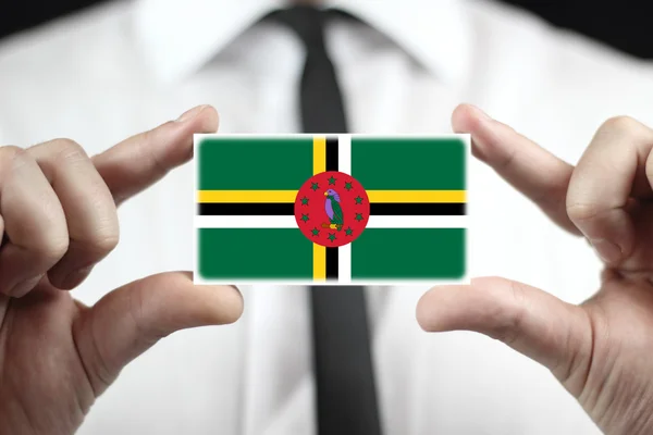 Affärsman som innehar ett visitkort med Dominicas flagga — Stockfoto
