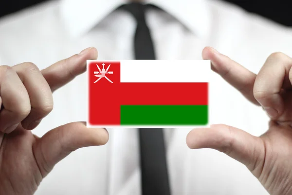 Uomo d'affari in possesso di un biglietto da visita con bandiera Oman — Foto Stock
