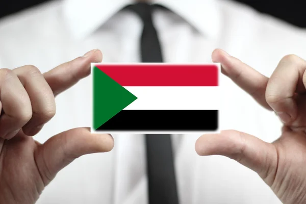 Biznesmen posiadania wizytówki z flaga Sudanu — Zdjęcie stockowe