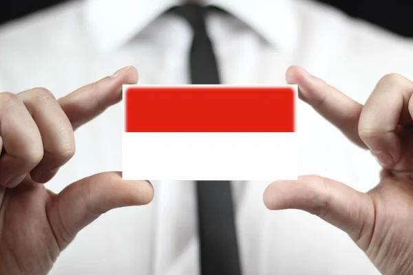 Uomo d'affari in possesso di un biglietto da visita con bandiera di Monaco — Foto Stock